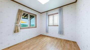 A room with two windows, wooden flooring, and a ceiling light.