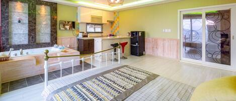 A modern kitchen with a central island, a dining area with a patterned rug, and a large sliding glass door leading to a balcony.