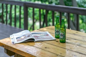 A wooden table with two Heineken beer bottles and an open magazine on a deck. - Hongcheon Valley Pension (Hongcheon)