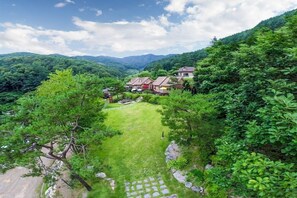 A residential area with houses surrounded by lush greenery and mountains in the background. - Hongcheon Valley Pension (Hongcheon)