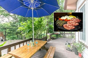 A wooden deck with a blue umbrella, a wooden table with drinks, and a grill with various meats. - Hongcheon Valley Pension (Hongcheon)
