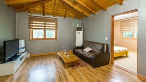 A cozy room with a wooden ceiling, a sofa, a TV, and a bed.