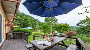 A wooden deck with a table, benches, and a large umbrella.
