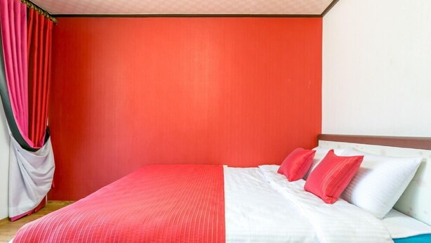 Una habitación con una cama, cortinas rojas y una pared roja.