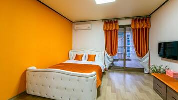 Un dormitorio con una cama, un televisor y una ventana con cortinas.