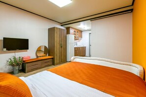 A hotel room with two beds, a TV, a mirror, a wardrobe, and a kitchenette. - Gatnaeum Pension (Geoje)