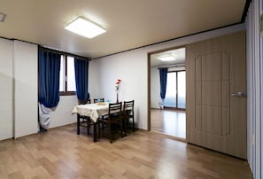 Comedor con mesa lista para cuatro, un espejo y una puerta que da a otra habitación.