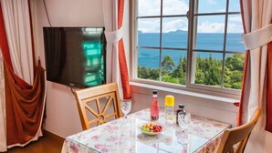 A room with a table set for two, a TV, and a window with a view of the sea. - Gaejul Trip Pension (Geoje)