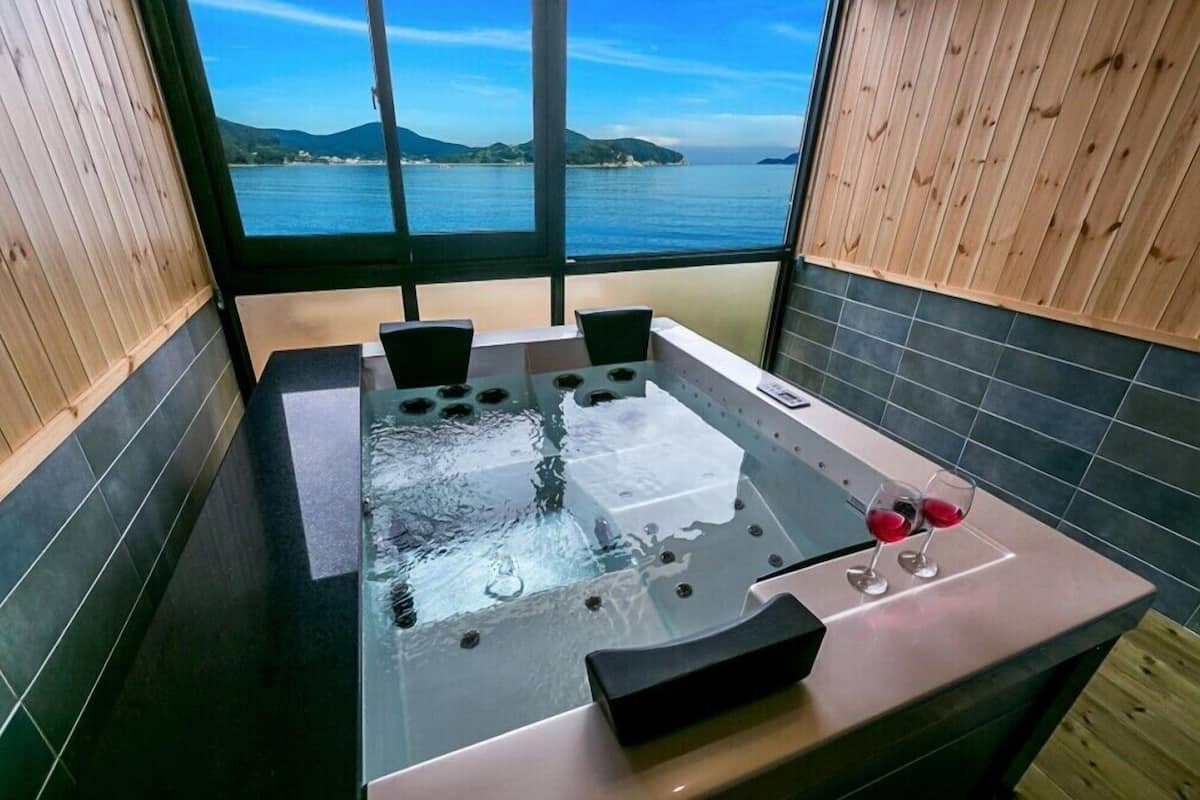 Un jacuzzi con vista al mar, paredes de madera y piso de baldosas.