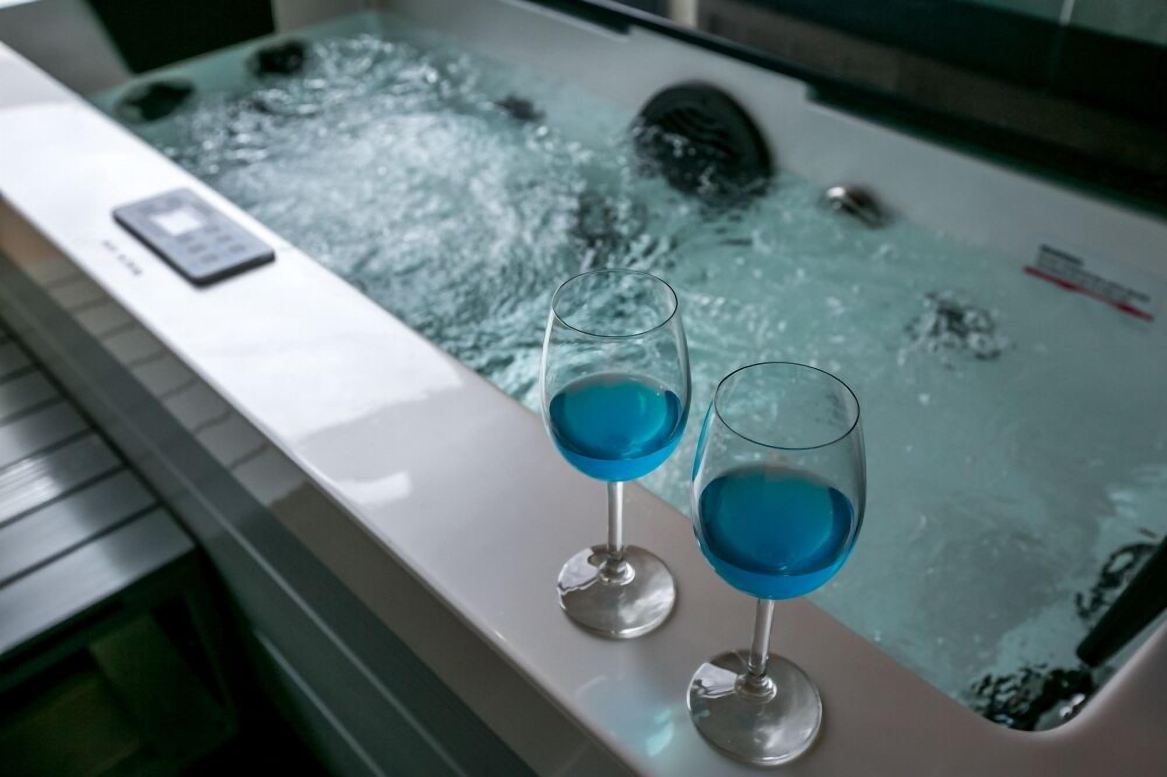 Una bañera con dos vasos de líquido azul, un control remoto y un letrero de seguridad en el borde.