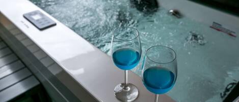 Una bañera con dos vasos de líquido azul, un control remoto y un letrero de seguridad en el borde.