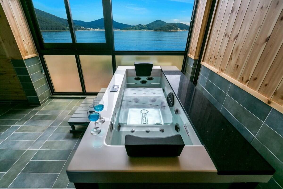 Una cocina moderna con un ventanal grande que da a un cuerpo de agua y colinas.