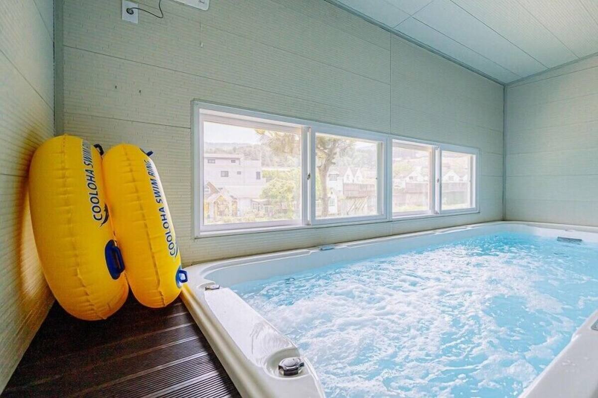 An indoor swimming pool with a view of houses through the windows.