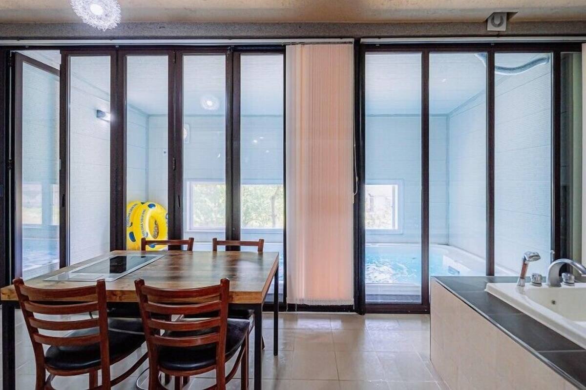 A dining area with a table and chairs, a sliding glass door leading to a balcony with a view, and a kitchen area with a bathtub.