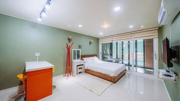Un dormitorio moderno con cama, mesitas de noche, escritorio y un amplio ventanal.