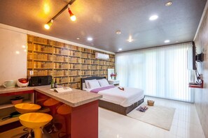 A modern hotel room with a kitchen area, a large bed, and a view of the outdoors. - Huenest pension (Gapyeong)