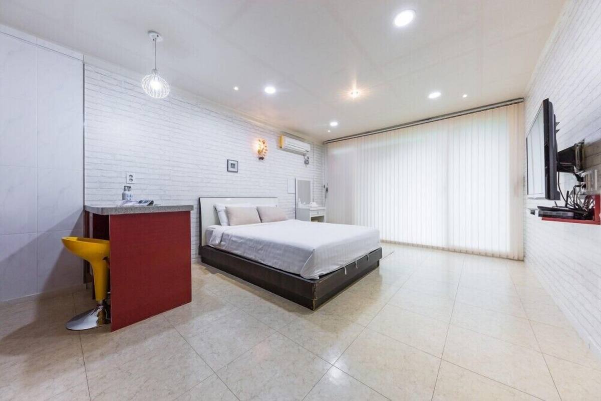A modern bedroom with a bed, a small desk, and a yellow chair.