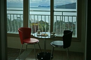 En balkong med ett bord och två stolar, med utsikt över en vattenyta och ett avlägset landområde.