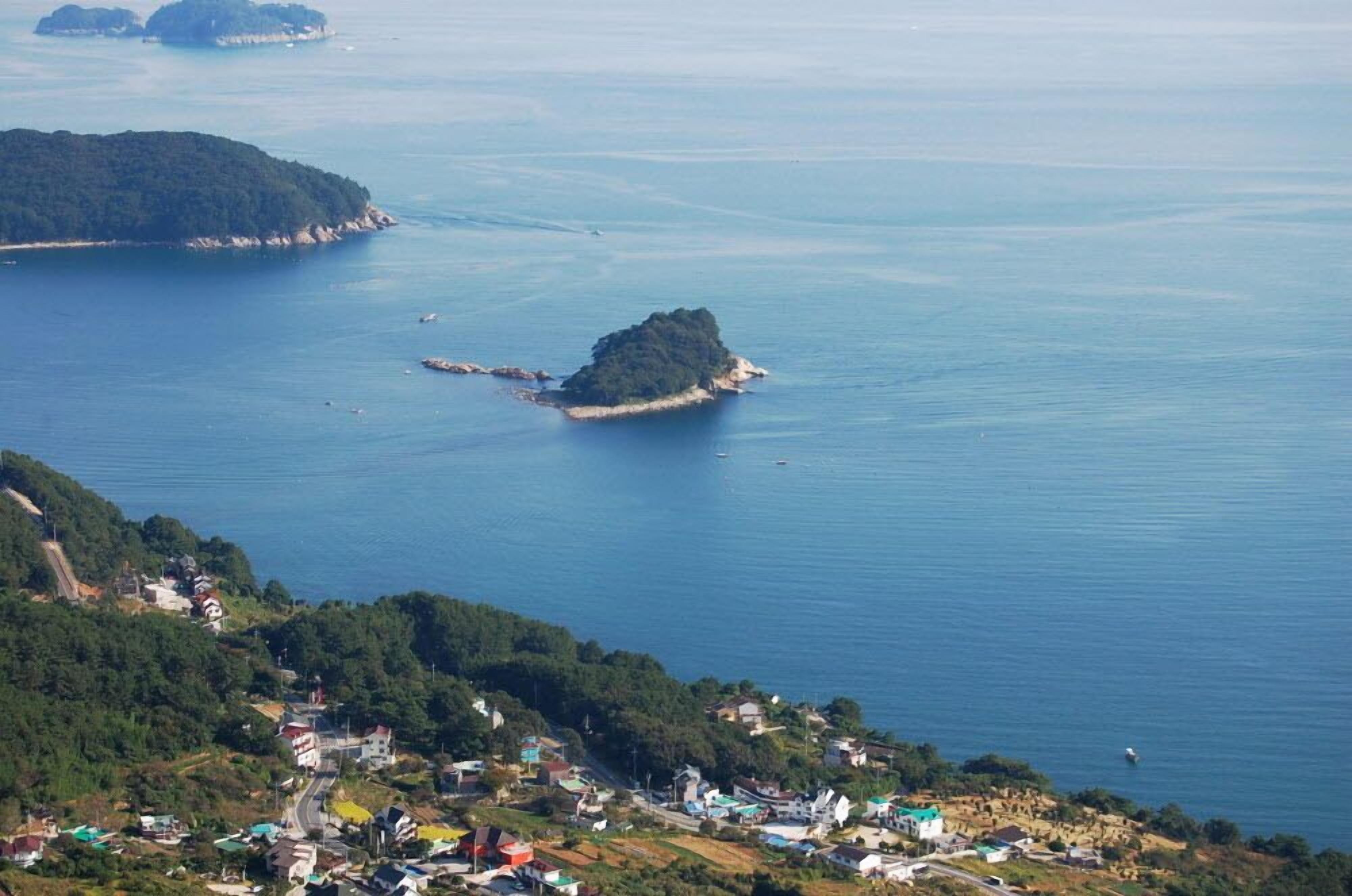 A coastal village with houses along the shoreline and a small island in the distance.