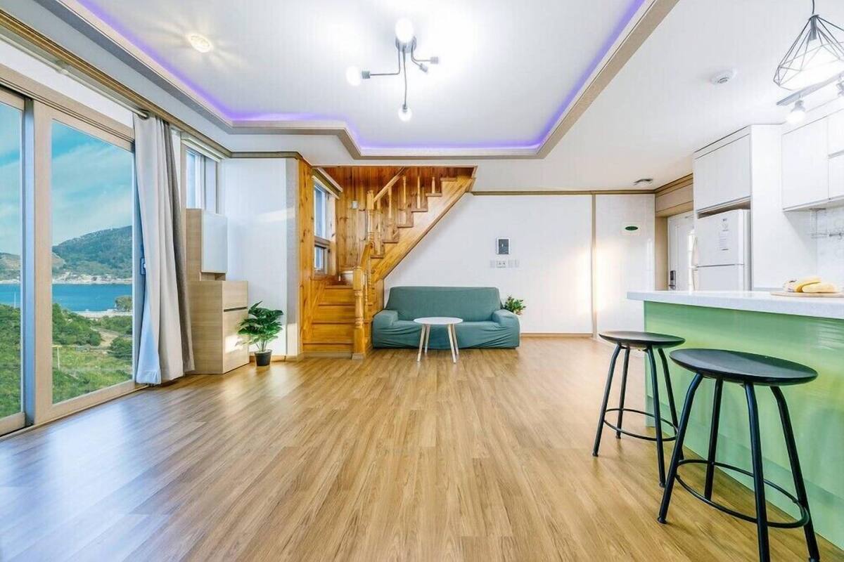 Un interior moderno con una escalera de madera, un sofá verde y una zona de cocina.