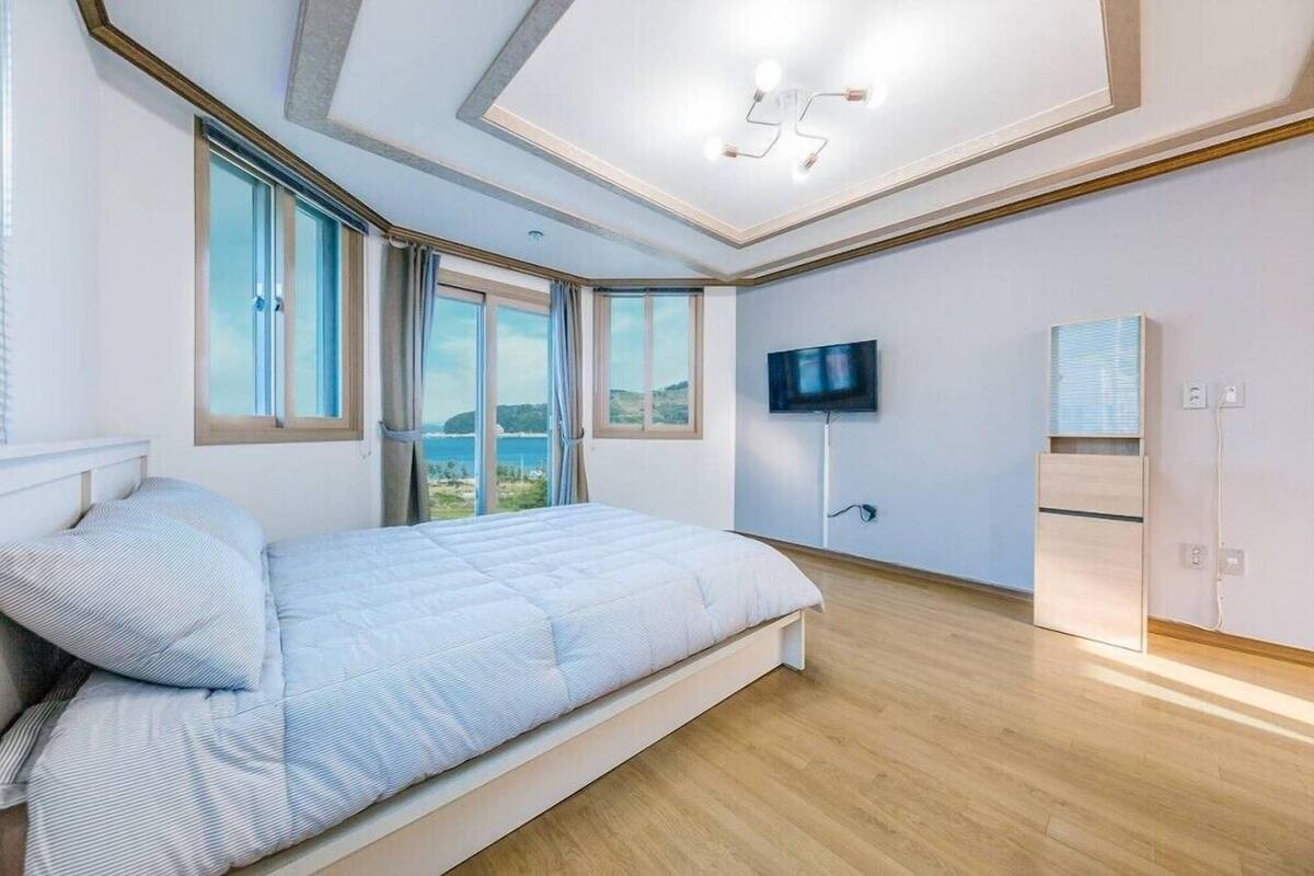 Un dormitorio moderno con una cama grande, televisión, armario y vistas al exterior.