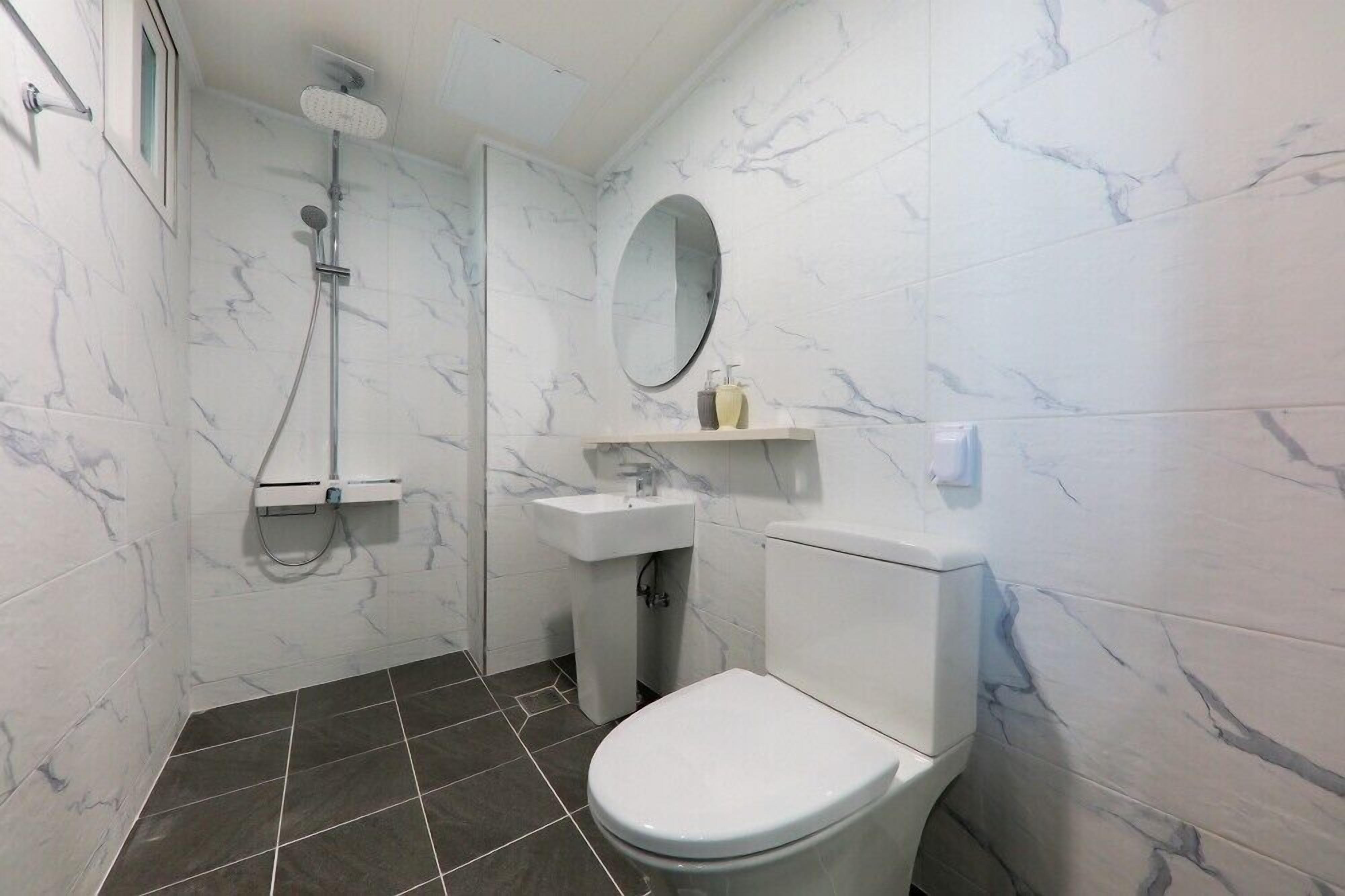 Une salle de bain équipée de toilettes, d’un lavabo et d’une douche.