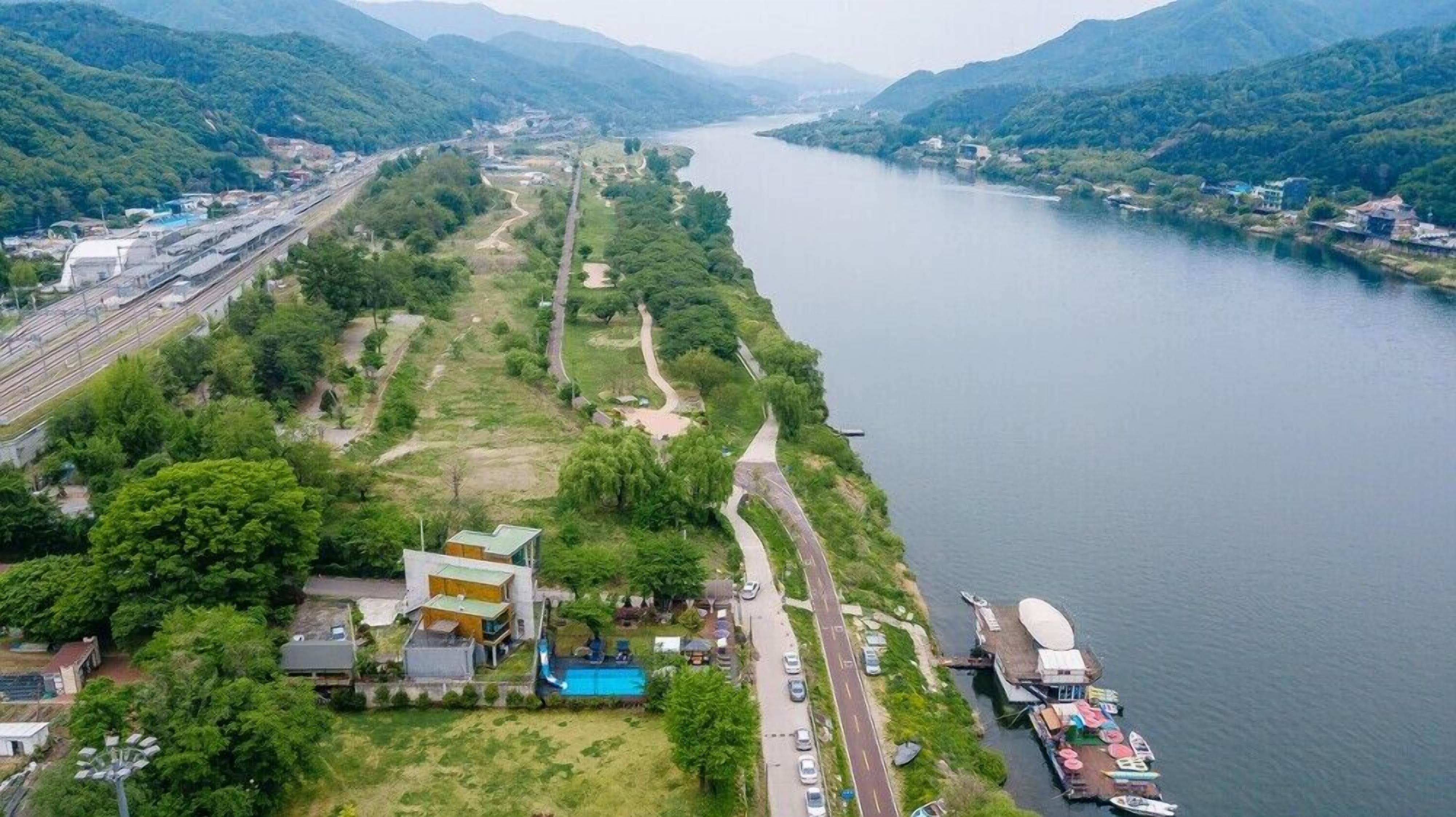 Une propriété située au bord de la rivière, dotée d’une piscine, d’un quai et d’une route menant à un pont.