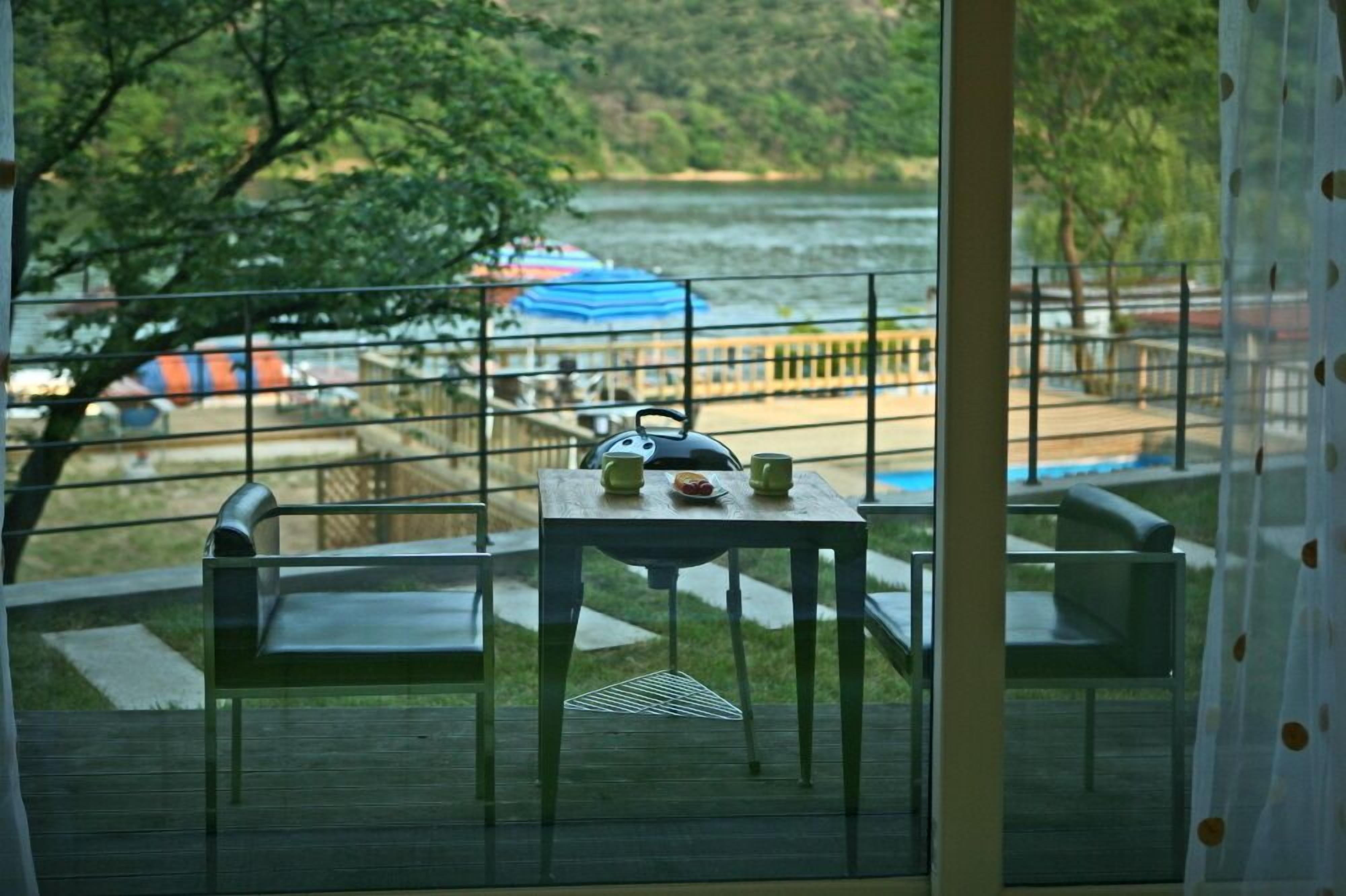 Ein Balkon mit Tisch und Stühlen mit Blick auf einen Fluss und einen Steg mit Booten.