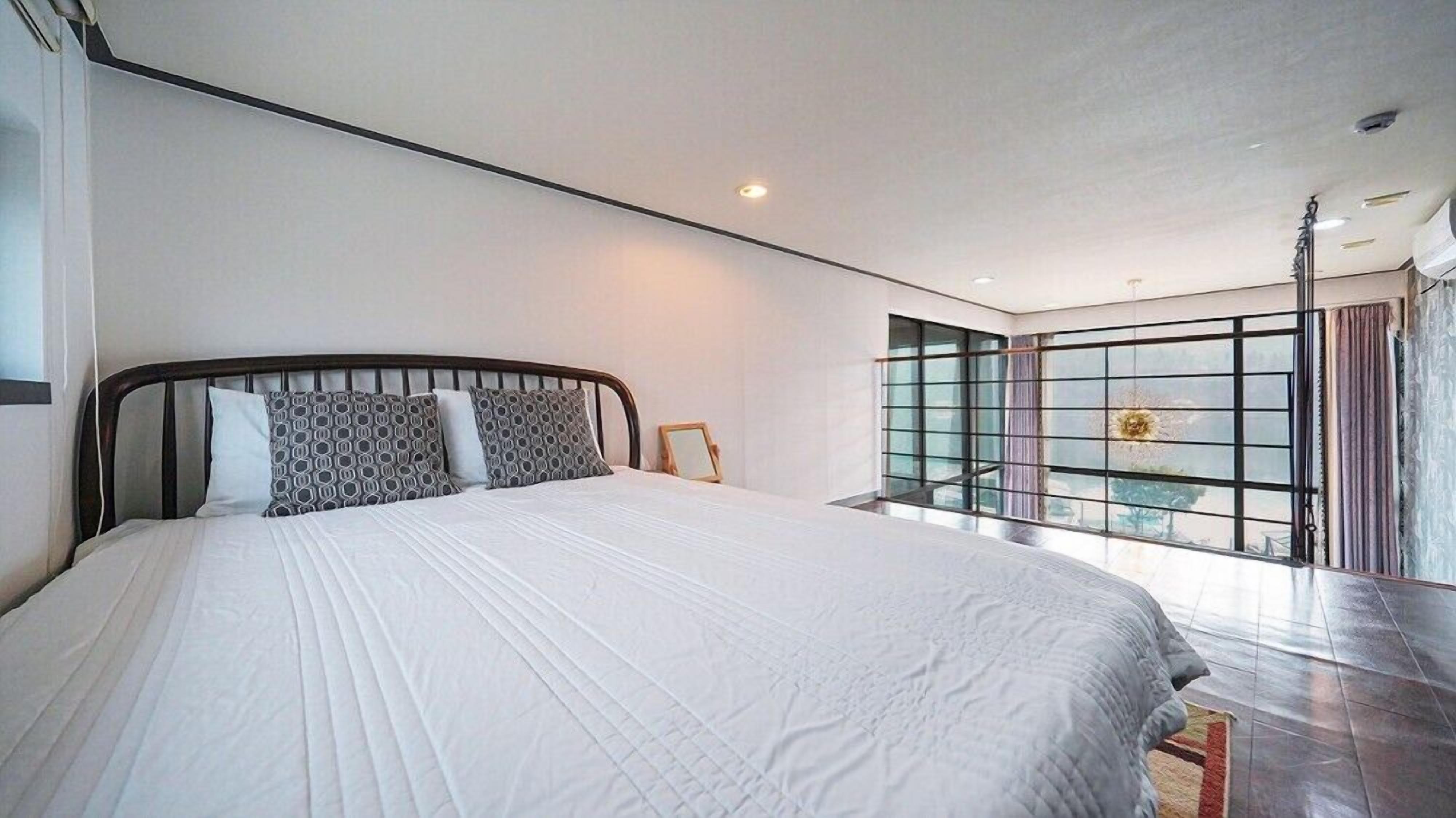 Un dormitorio moderno con una cama grande, un ventanal con vistas y una lámpara en el techo.