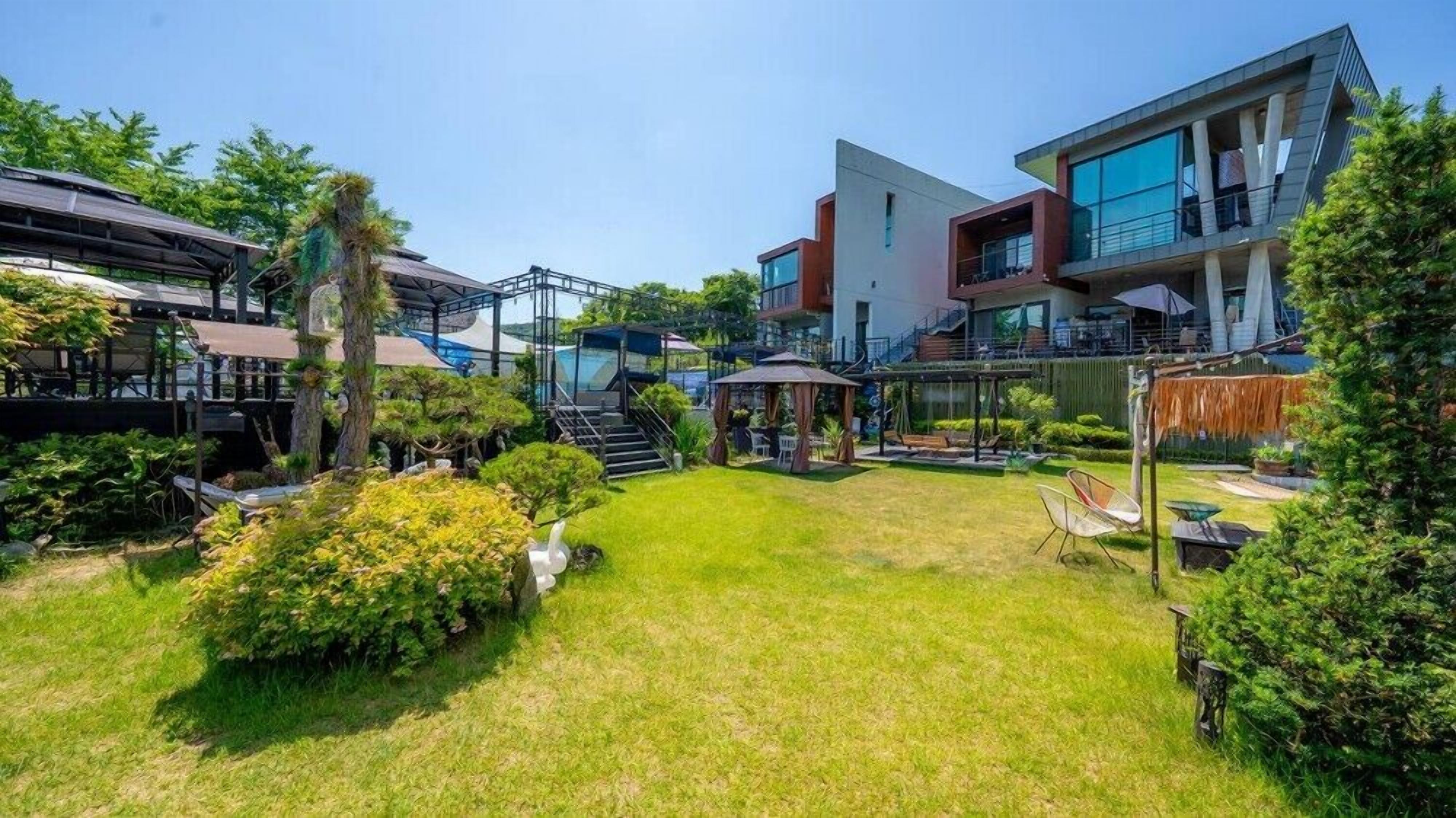Un hotel moderno con un patio amplio, mobiliario exterior y una zona de piscina.