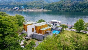 Una casa moderna con piscina, rodeada de exuberante vegetación y un lago.