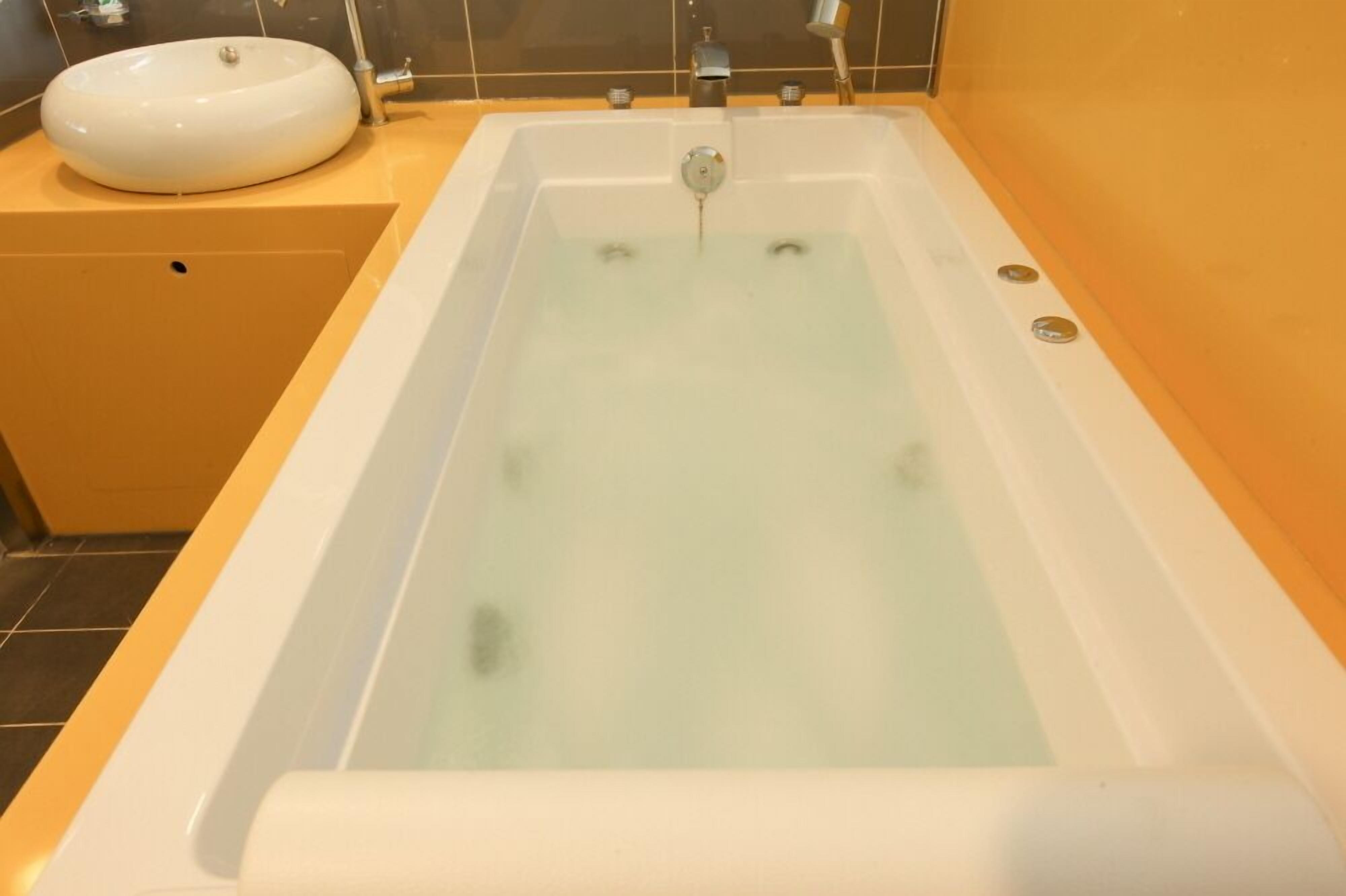 A bathtub with a white sink and a faucet.