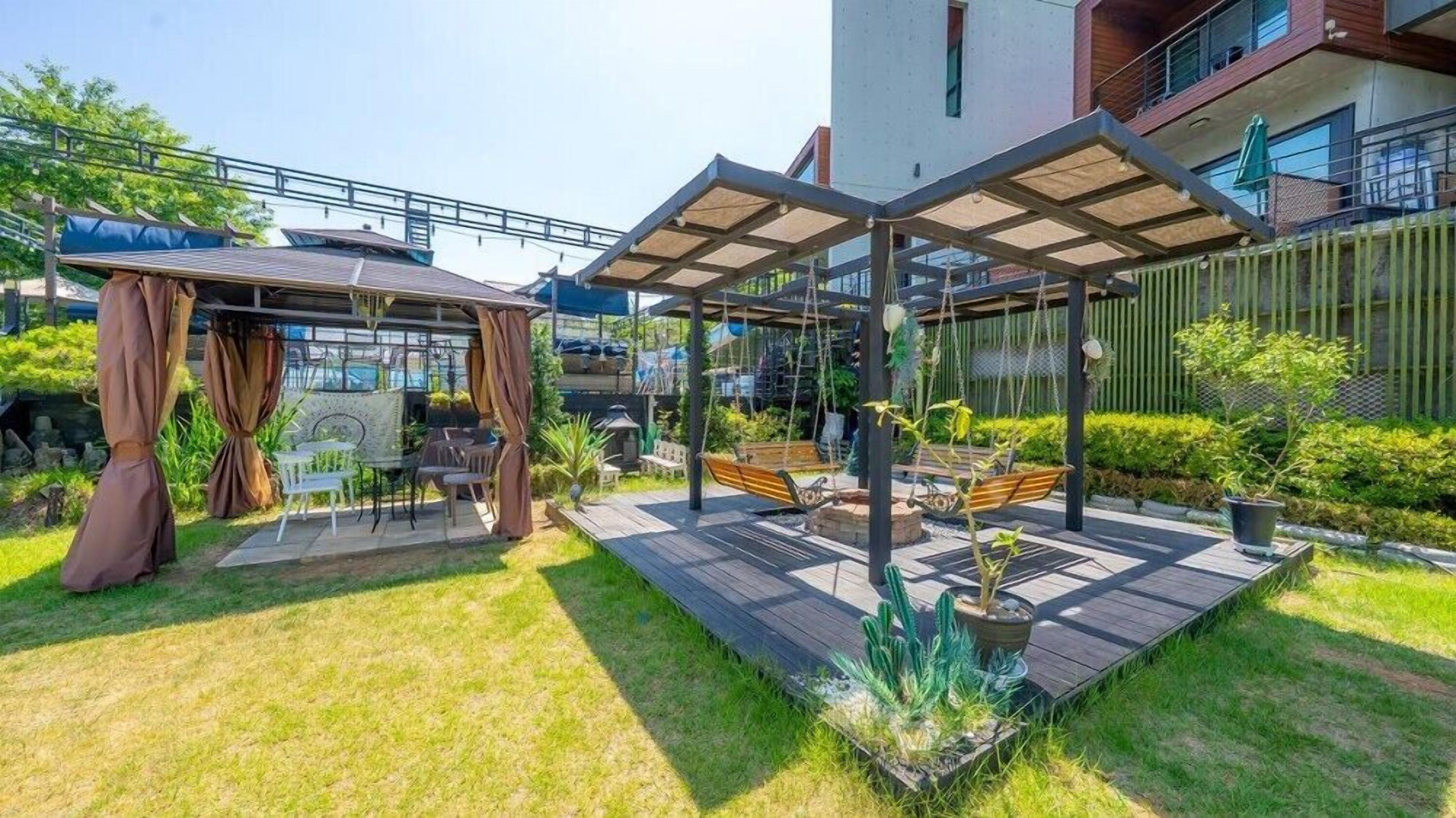 Un patio con pérgola, mobiliario exterior y jardín.