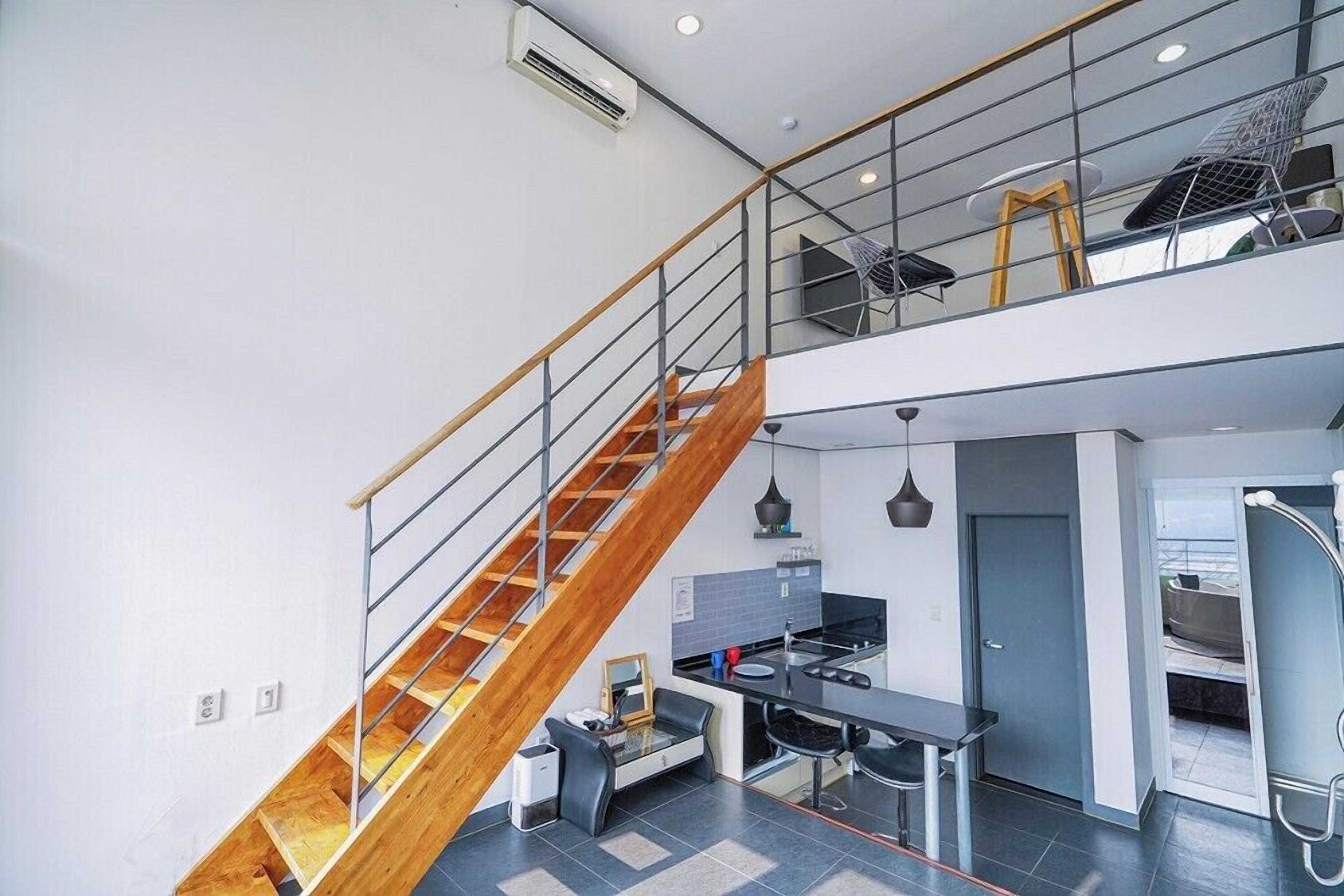 Una cocina moderna con una isla central, una escalera de peldaños de madera y un entresuelo con asientos.