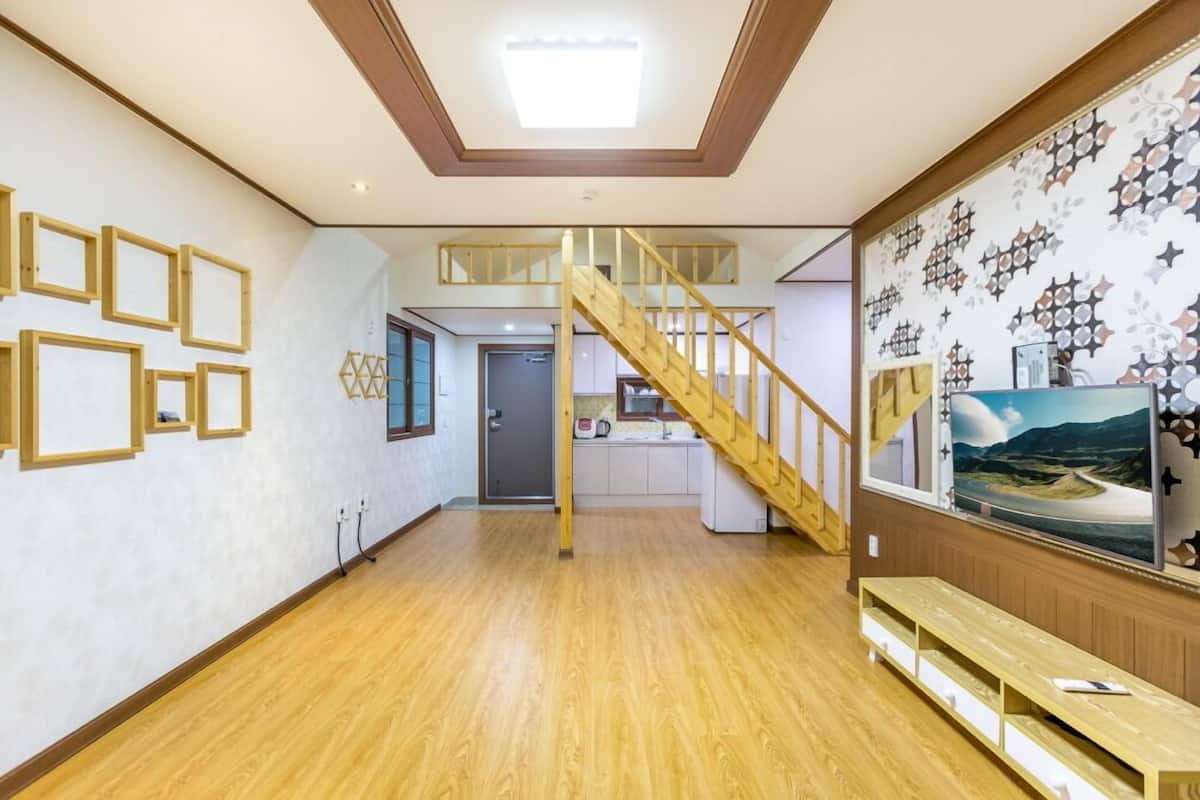 Una habitación amplia con una escalera de madera, una zona de cocina y un gran mural en la pared.
