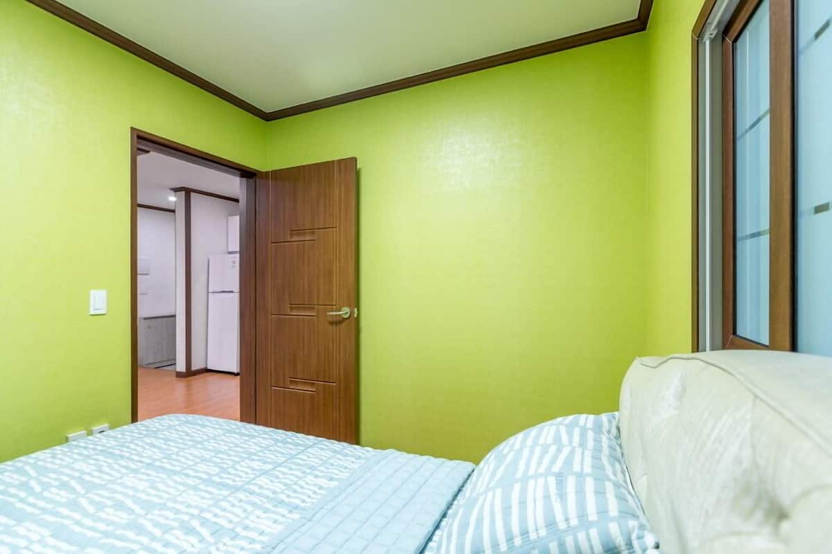 Un dormitorio con una cama, una puerta y una ventana.