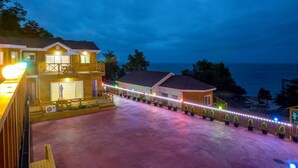 A two-story building with a balcony, a covered patio, and a view of the ocean. - Neulpureun Pension (Yeongdeok)