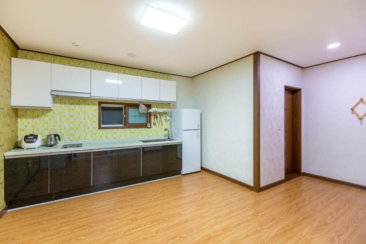 Cocina con armarios blancos, microondas y refrigerador.