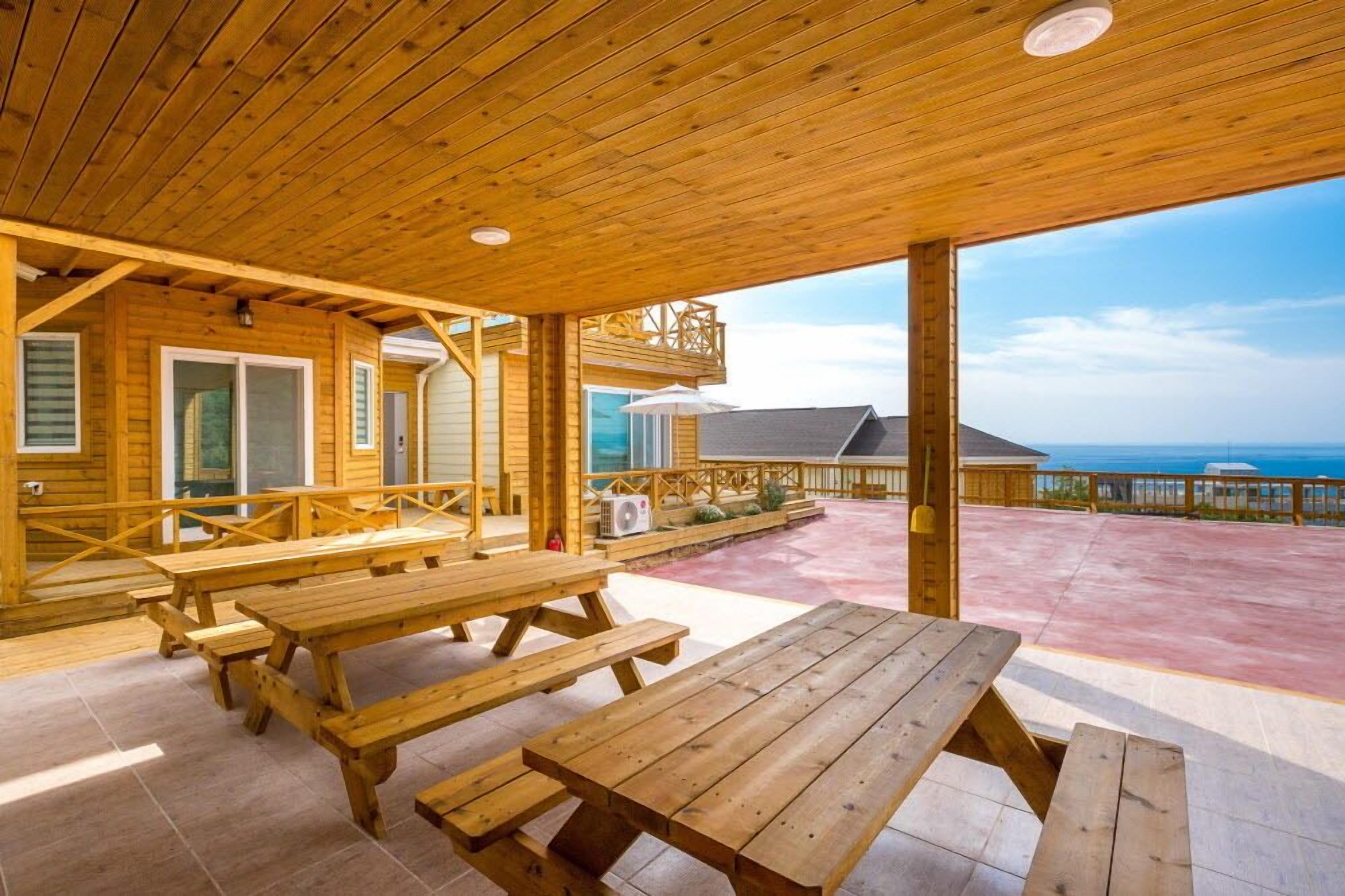A wooden deck with picnic tables overlooking a scenic view.