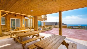 A wooden deck with picnic tables overlooking a scenic view.