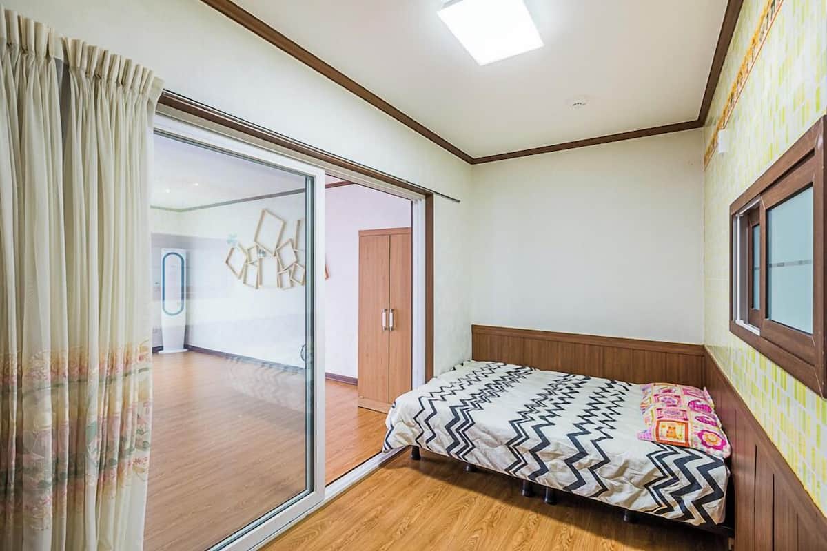 Un dormitorio con una cama, un ventanal corredero y una ventana.