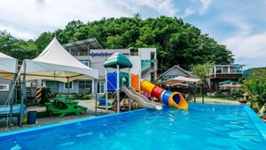 A swimming pool with a water slide, picnic tables, and a tent. - Mulga Pension (Gapyeong)
