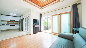 A modern apartment with a kitchen, a living area with a sofa, and a balcony with a view. - Mulga Pension (Gapyeong)