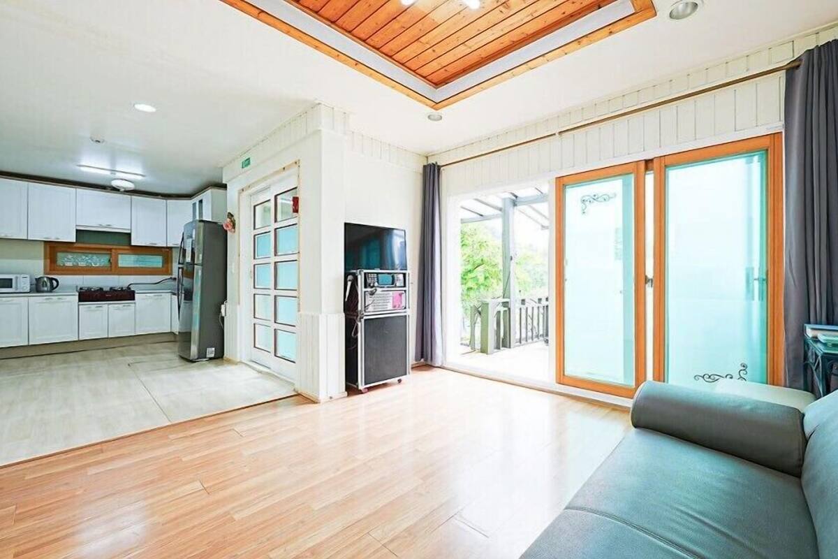 A modern apartment with a kitchen, a living area with a sofa, and a balcony with a view.