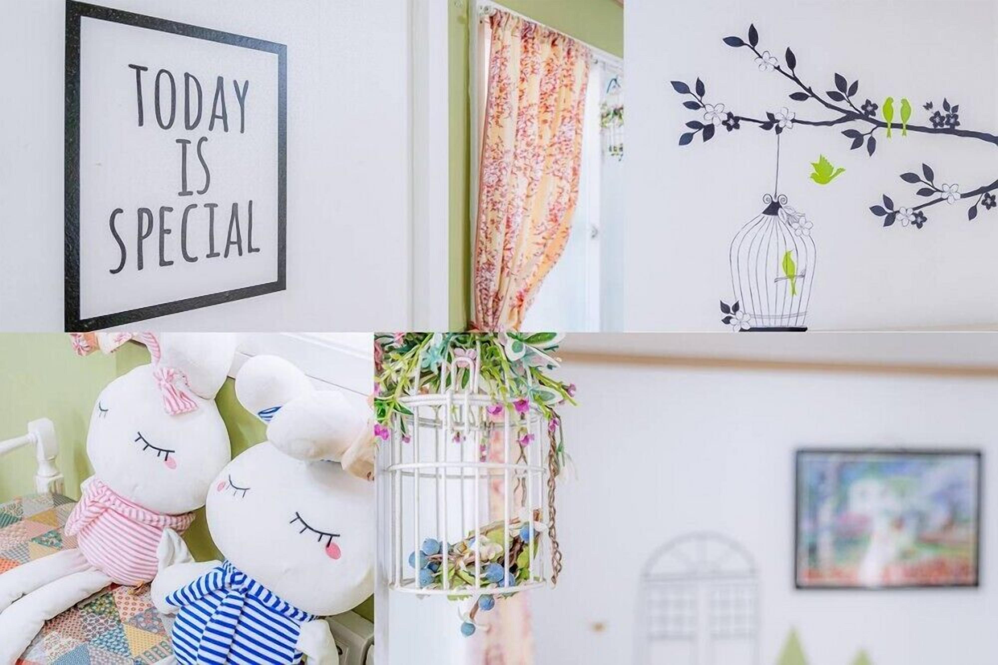 Eine Wand mit einem Schild, das 'TODAY IS SPECIAL' zeigt, einem blumigen Vorhang, einer Wanddekoration mit Vögeln und Blumen, zwei Plüschtieren und einem Vogelkäfig mit Blumen.