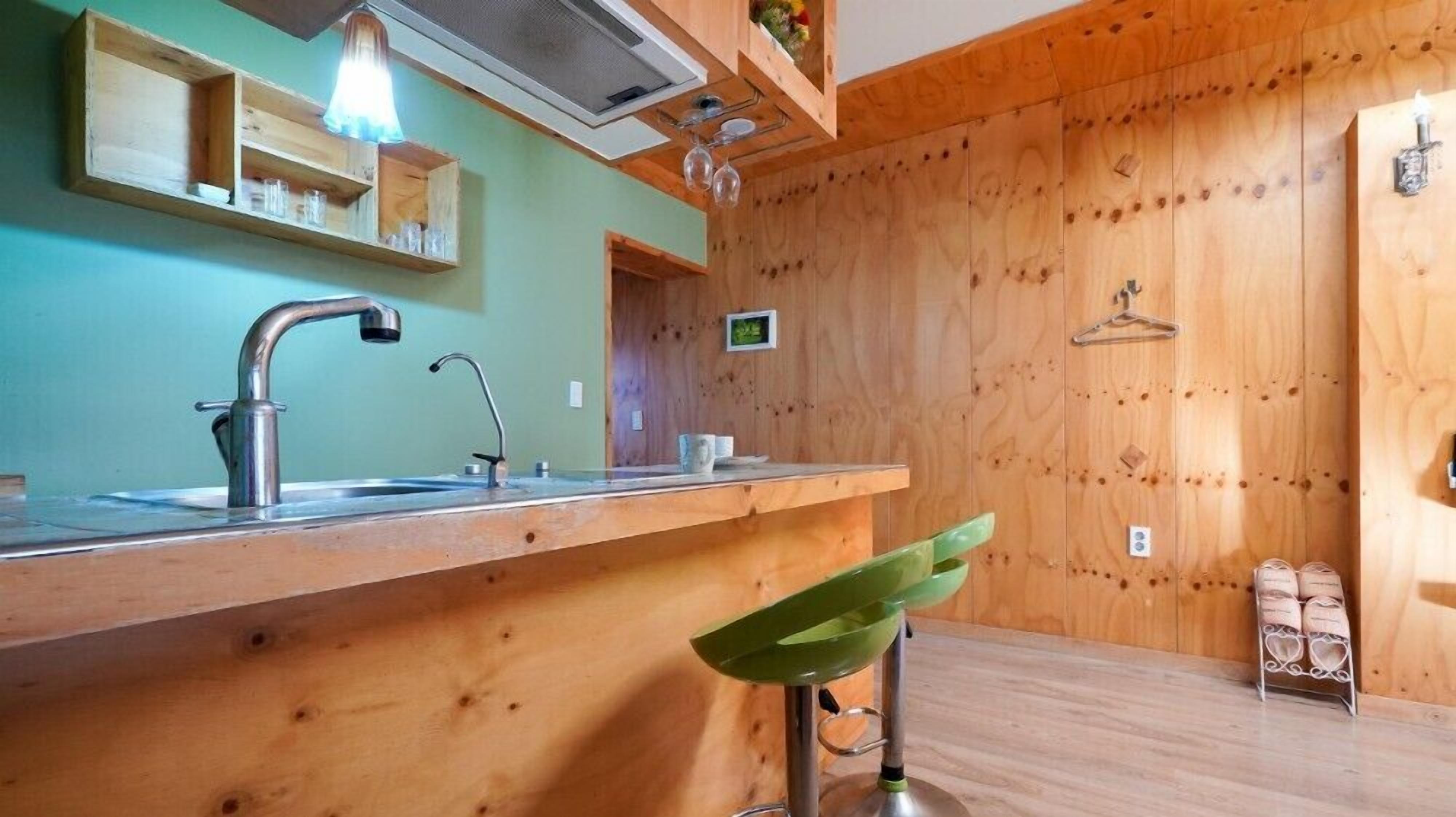 A kitchen with wooden cabinets, a sink, and a green bar stool.