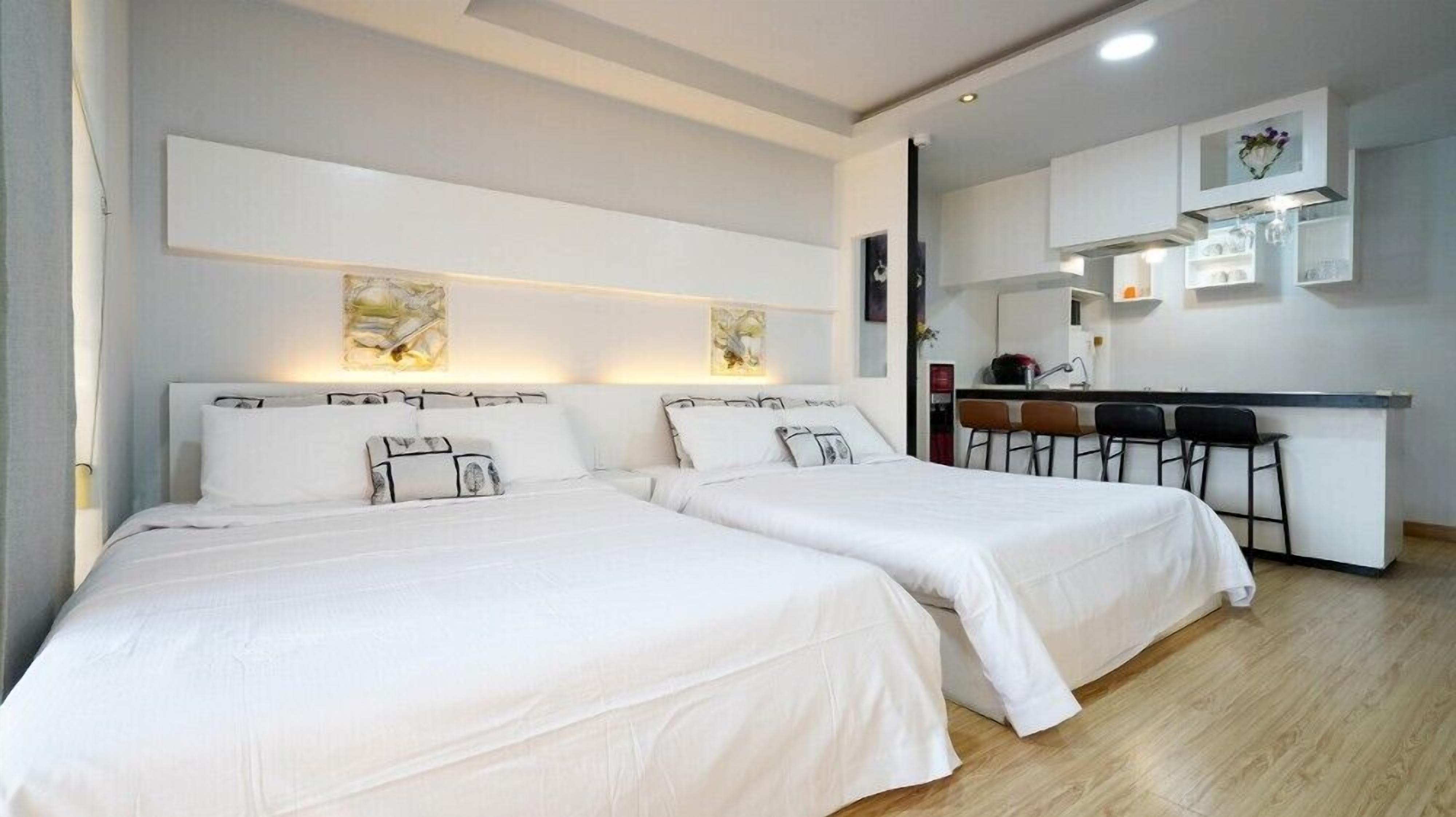 Habitación de hotel con dos camas, kitchenette y un pequeño comedor.