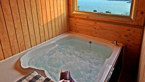 A wooden cabin with a hot tub and a view of a lake. - Pado Hyanggi Pension (Geoje)