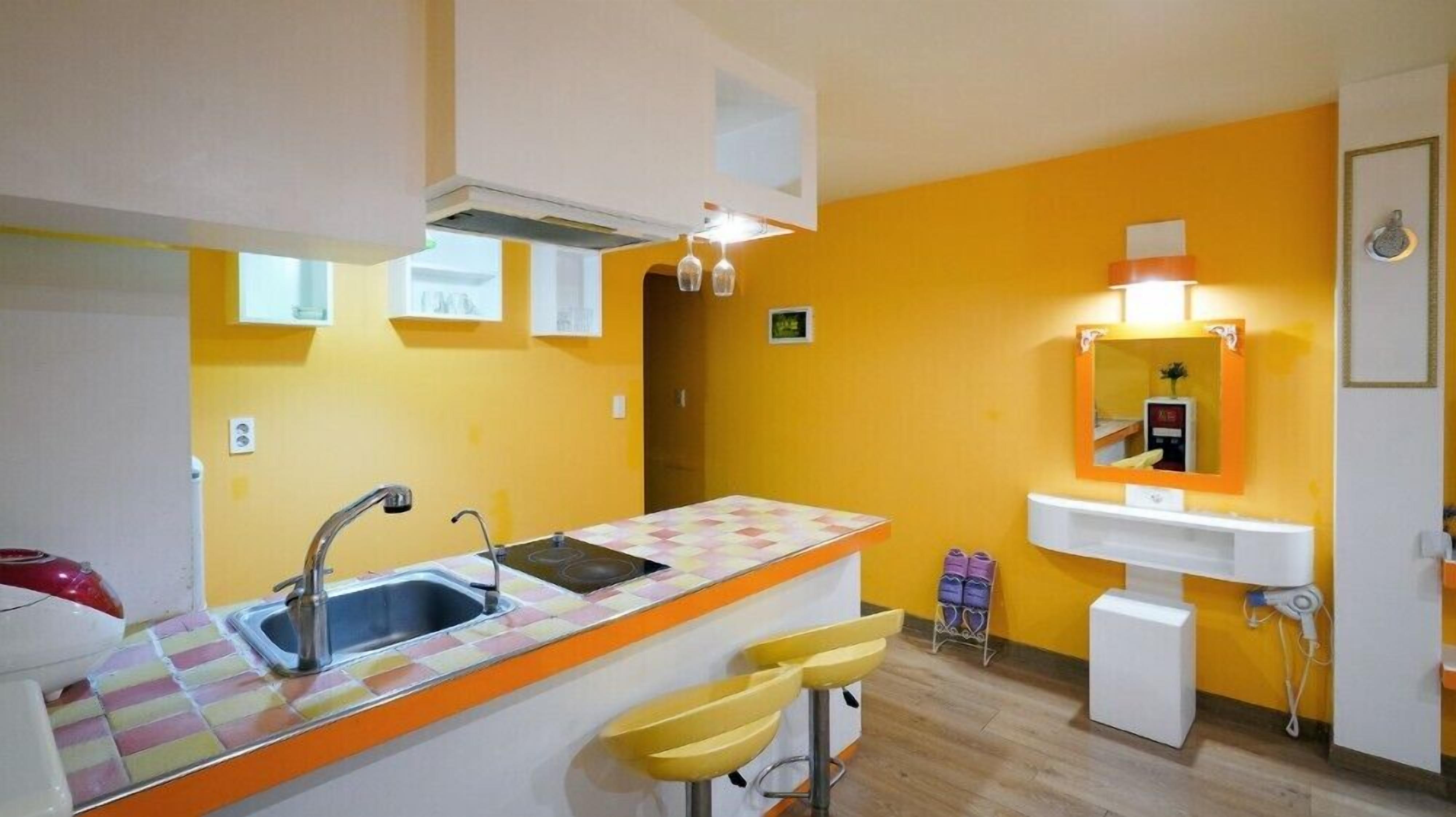 A compact kitchen with a sink, bar stools, and a small countertop.