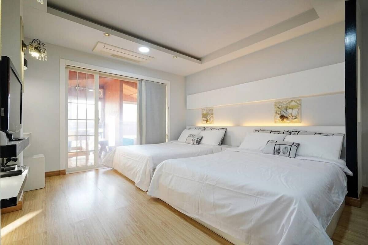 A hotel room with two beds, a sliding glass door, a coffee machine, and artwork on the walls.